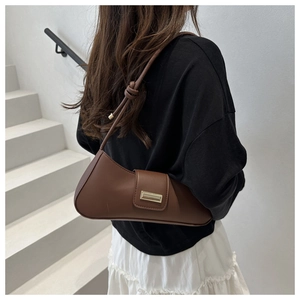 Détail du sac baguette marron avec nœud sur la bandoulière et boucle métallique dorée