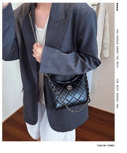 Close-up of quilted black leather shoulder bag with golden chain and logo detail