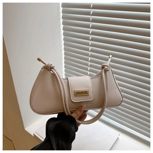 Close-up of cream-white leather shoulder bag featuring unique knotted strap and gold buckle