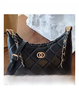 Detailed view of quilted black leather bag with gold-tone chain and circular logo