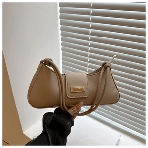 Detailed view of beige baguette bag featuring a chic knotted strap and gold metal buckle
