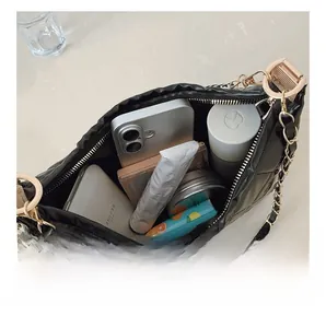 Interior view of black quilted crossbody bag showing storage for phone and makeup