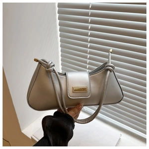 Detail of silver matte underarm bag featuring a gold buckle and knotted strap design