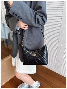Close-up of black quilted shoulder bag with gold chain strap and ring buckle