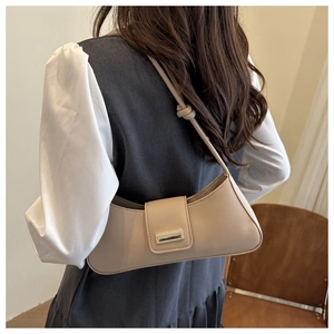 Détail du sac baguette beige avec boucle dorée et bandoulière à nœud élégante