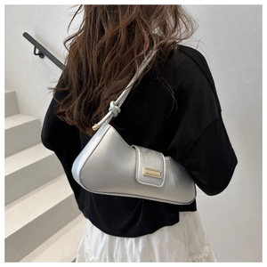 Detail of silver metallic underarm bag showing shoulder strap knot and sleek finish