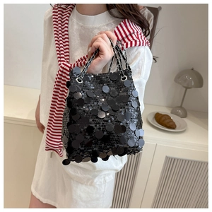 Détail du sac seau à paillettes noires avec bandoulière chaîne argentée sur fond crème