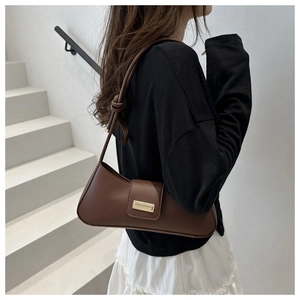 Detail of minimalist brown leather shoulder bag with gold buckle and knot strap detail