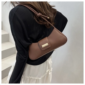 Detail of a brown baguette bag with a metal buckle and knot-design shoulder strap