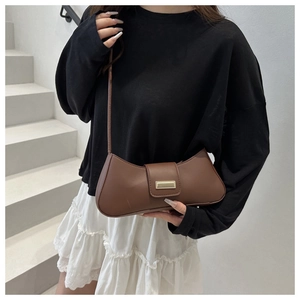 Detail view of coffee brown baguette bag with golden buckle and sleek curved bottom