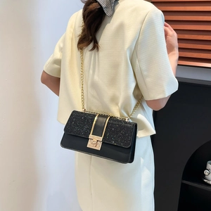 Elegant black sequin chain crossbody bag with gold buckle shown on shoulder