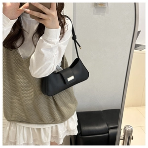 Mirror selfie showing the black leather baguette underarm bag with metal buckle