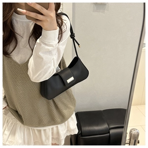 Selfie miroir montrant le sac baguette noir avec fermoir doré et détail de bandoulière nouée