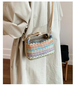 Detail of colorful geometric woven straw bucket bag with beige PU strap and gold clasp