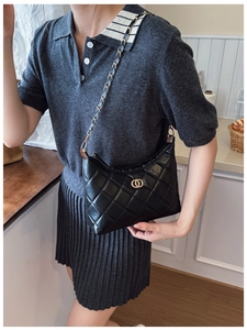 Détail d'un sac à bandoulière en cuir noir matelassé avec chaîne dorée et logo anneau