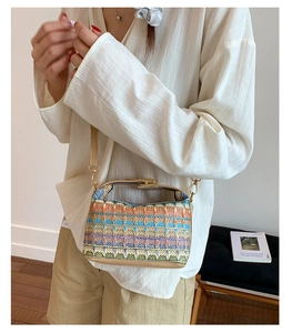 Detail of bohemian woven straw bucket bag with colorful geometric patterns and gold lock