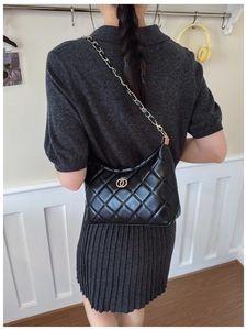 Close-up of black quilted shoulder bag with gold chain strap and ring hardware