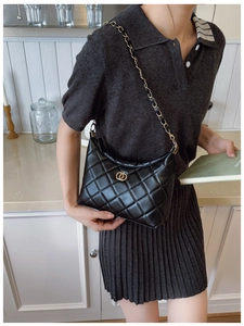 Détails d'un sac à bandoulière noir matelassé avec chaîne dorée et logo élégant