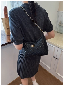 Détail du sac matelassé noir avec chaîne dorée et bords plissés élégants