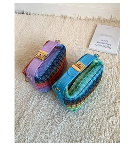 Detail of colorful woven straw bags with wave patterns, leather handles and gold metal locks