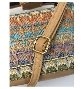 Detailed macro view of colorful straw woven bag with leather strap and golden metal buckle