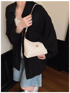 Gros plan d'un sac porté épaule matelassé beige avec chaîne dorée sur un mannequin