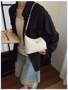 Sac bandoulière blanc matelassé avec chaîne dorée et boucle à double anneau sur un mannequin