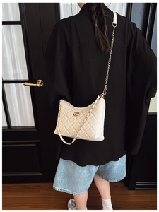 Close-up of cream quilted hobo bag with gold interlocking logo and chain strap