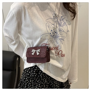 Detail of burgundy mini bag with snake skin texture and silver bow chain strap