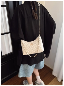 Detail of cream quilted leather shoulder bag featuring a gold buckle and chain strap