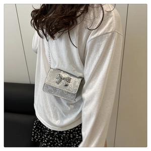 Detail of silver bow-knot mini crossbody bag with snake texture and elegant chain strap