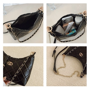 Detail view of black quilted crossbody bag showing gold logo, chain strap and interior space