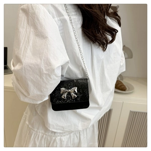 Detailed view of mini chain bag with snake skin texture and silver bow buckle