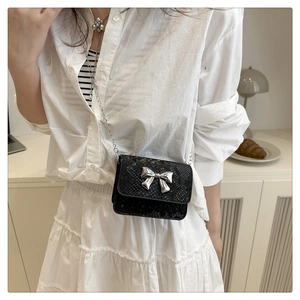 Close-up of black snake texture mini crossbody bag with silver bow and chain strap