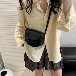 Minimalist black semi-circular saddle bag in glossy leather with slim shoulder strap