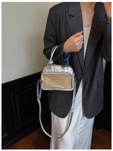 Silver Ita Bag with clear window and metallic finish shown with a stylish grey blazer