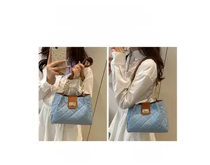 Detail of light blue quilted tote with gold chain handle and two carrying styles