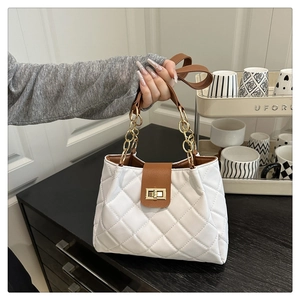 Detalle de bolso acolchado blanco con solapa marrón y asa de cadena dorada elegante
