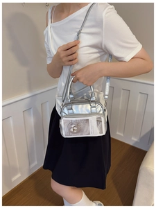 Detail of silver metallic tote bag featuring a clear front pocket and top handles