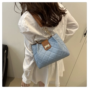 Detalle del bolso acolchado azul claro con cadena dorada y detalles en marrón
