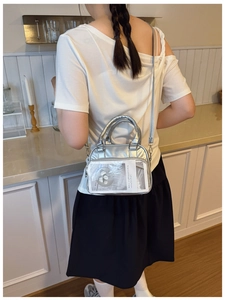Detail of silver metallic tote bag with clear front pocket and adjustable shoulder strap