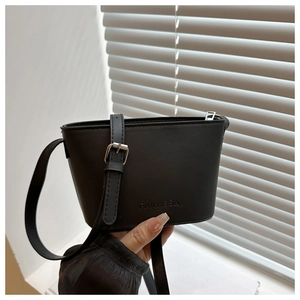 Close-up of black crossbody bucket bag with textured brand embossing and silver hardware