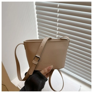 Detail of a beige PU leather bucket bag featuring embossed logo and adjustable strap
