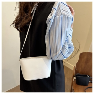 Detail of white leather mini bucket bag with embossed logo and matching strap