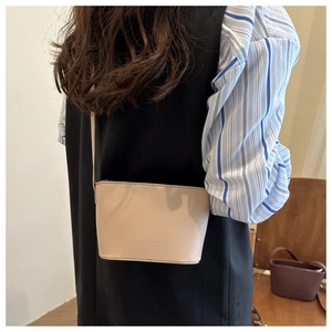 Chic beige leather bucket bag styled on shoulder showing compact size and sleek design