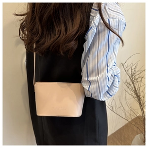 Close-up of beige FANYISSA leather crossbody bag showing the embossed brand logo detail