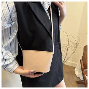 Detail view of a minimalist beige crossbody bag worn by a model for a daily commute look