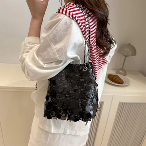 Elegante borsa a secchiello con paillettes nere e tracolla a catena indossata da modella