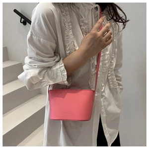 Detail of a pink leather crossbody bag showing the branding and textured matte surface
