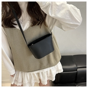 Detail of black leather bucket bag with embossed logo and slim crossbody shoulder strap